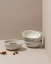 A white stoneware cereal bowl is displayed against a neutral background. The bowl appears modern and simple in design with a matte finish.
