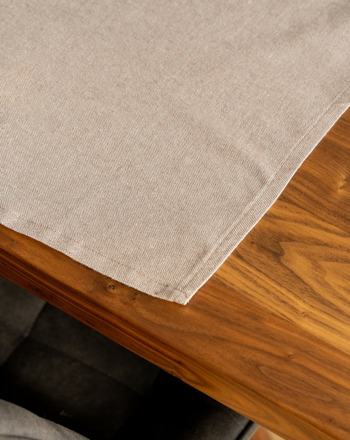 A Taupe cotton placemat is laid out on a wooden table.
