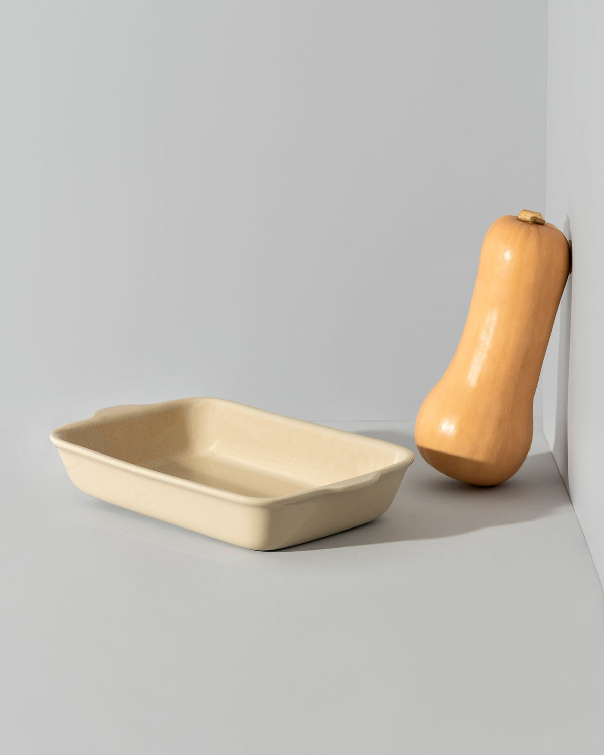 A stack of rectangular stoneware baking dishes in beige, blue, and green colors.