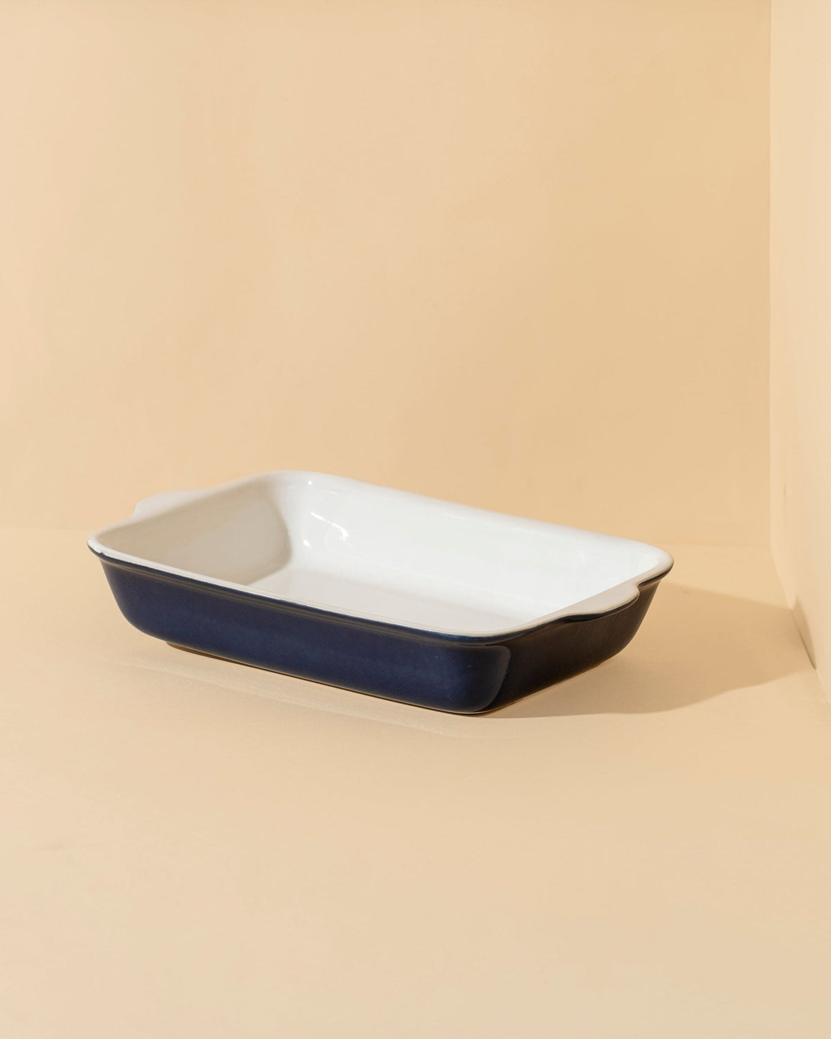 A stack of rectangular stoneware baking dishes in beige, blue, and green colors.