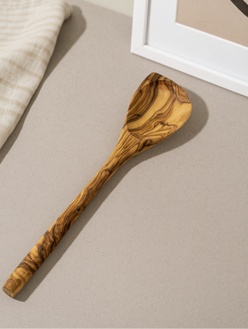 Wooden spoon on a beige surface with a framed picture in the background
